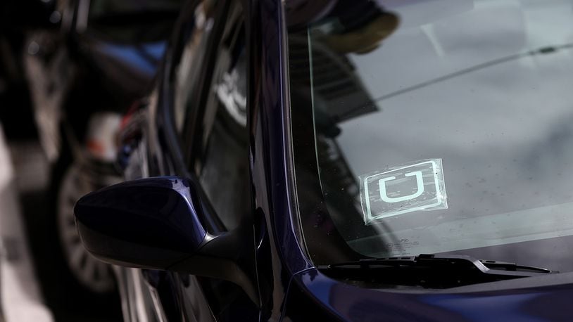 A sticker with the Uber logo is displayed in the window of a car. (Photo by Justin Sullivan/Getty Images)