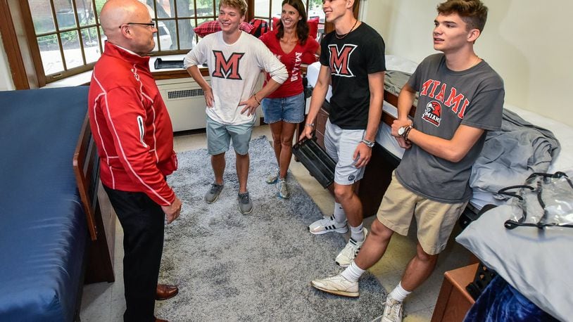 Miami University President Gregory Crawford, left, meets with triplets Luke, second from left, Jonas and Dominic Keller, right, with their mom, Theresa, as they help Dominic move into his dorm while students and parents negotiate the crowded streets and dorm halls for move in day Thursday, August 22 at Miami University in Oxford. The brothers are all starting as school at Miami but living in different dorms. NICK GRAHAM/STAFF