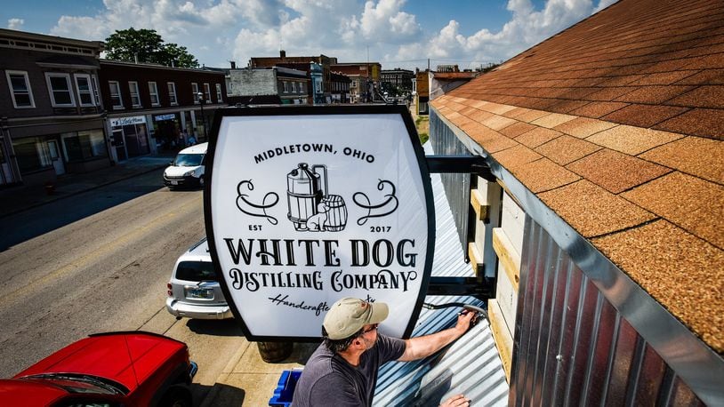 Jim Edwards with Digital Visuals installs signage outside of White Dog Distilling Company on Central Avenue in Middletown.