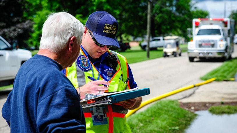 Ron Crysel, left, talks in May 2017 to Greg Brooks with Butler County Emergency Management Agency to survey damage to his home after flood waters filled the basement and lower level on East Ritter Street in Seven Mile. NICK GRAHAM/FILE