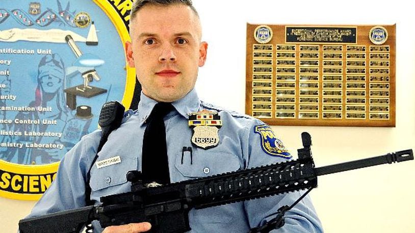 Philadelphia police tweeted a photo of Officer Krzyszpof Wrzesinski posing with the weapons, warning parents to "make sure your weapons are secured." (Photo via Philadelphia police)
