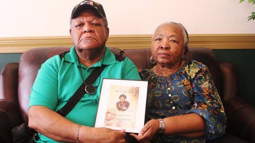 John Golden and his wife hold up the funeral program for his mother, Curliene Golden, at a press conference on Tuesday, July 9, 2019, in Jonesboro, Georgia.