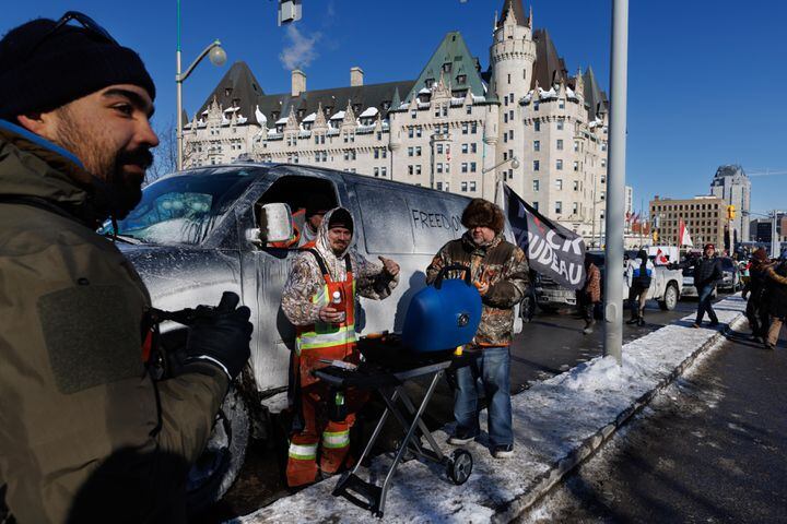 Supporters of the convoy of truckers protesting coronavirus vaccine mandates and pandemic restrictions grill hot dogs on a street near Parliament Hill in downtown Ottawa, Canada, Jan. 29, 2022. (Nasuna Stuart-Ulin/The New York Times)