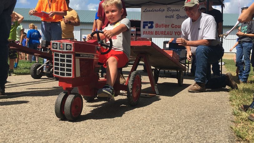 Four-year-old Bryce Clawson competes in the Kiddy Tractor pull, with the help of Farm Bureau member Dave Lierer on Friday, July 27, at the Butler County Fair. JACKIE OSBORNE/STAFF