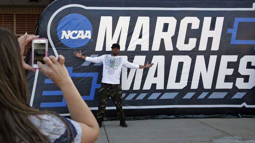 Christy Flint photographs Mac Heath with the March Madness sign before the NCAA First Four games began. TY GREENLEES / STAFF