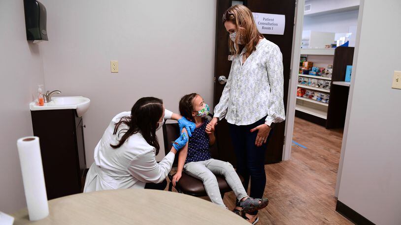 Katie Perry gives a vaccine to a child at Cedar Care Pharmacy in Cedarville. CONTRIBUTED