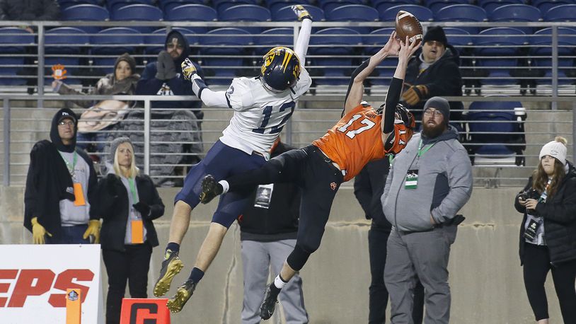 Versailles High School sophomore Michael Osborne catches a touchdown pass over Kirtland's Will Sayle during the Division V state championship game on Saturday night at Tom Benson Hall of Fame Stadium in Canton. Versailles won the game, 20-16. Michael Cooper/CONTRIBUTED
