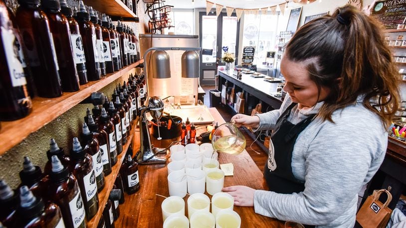 Taylor Hooker pours hot wax for candles at Petals & Wicks on Main Street in Hamilton Tuesday, April 2, 2019. Owner Sherry Hoskins recently expanded her candle business to add lotion, bath bombs, and other items to gear up for the opening of Spooky Nook Sports complex that is slated to open in 2021. NICK GRAHAM/STAFF