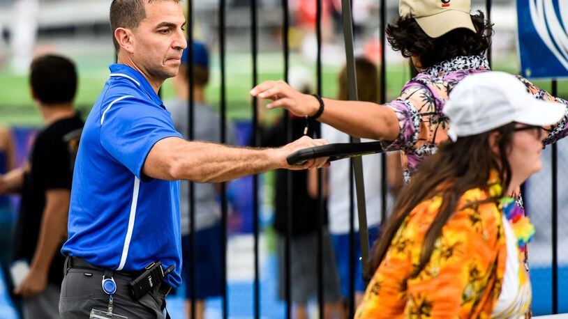 Hamilton High School Principal John Wilhelm uses a metal detector wand to check students at the student entrance before the Sept. 7 football game at Hamilton High School’s Virgil M. Schwarm Stadium. NICK GRAHAM/STAFF