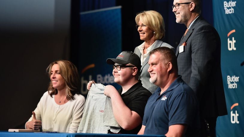 Butler Tech student Randy Owens, middle, holds up a shirt for his new employer, Richards Industries, during a signing day ceremony at Butler Tech in Fairfield Township Friday, April 12, 2019. Twenty-five students signed to work for companies they did internships with during the school year. NICK GRAHAM/STAFF