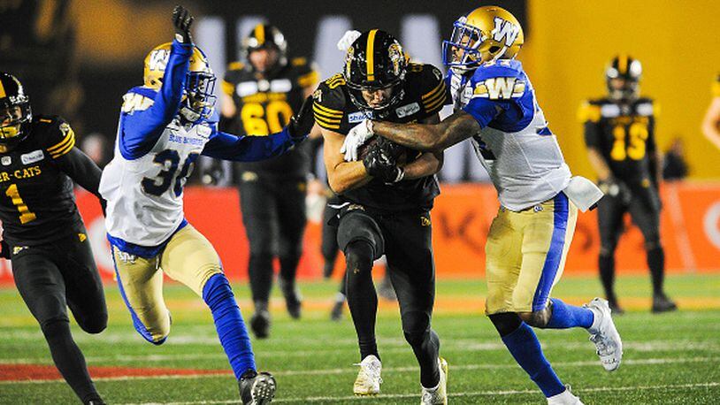 CALGARY, AB - NOVEMBER 24: Jaelon Acklin #80 of the Hamilton Tiger-Cats runs the ball against Brandon Alexander #37 (R) and Winston Rose #30 of the Winnipeg Blue Bombers during the 107th Grey Cup Championship Game at McMahon Stadium on November 24, 2019 in Calgary, Alberta, Canada. (Photo by Derek Leung/Getty Images)