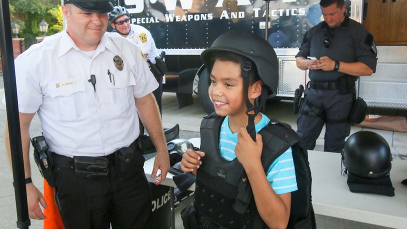 Hamilton Police Officer Scott Arbino helps David Trinidad, 8, try on a SWAT uniform during an Open  House at the Hamilton Police Department headquarters, Thursday, Aug. 10, 2017. GREG LYNCH /  STAFF