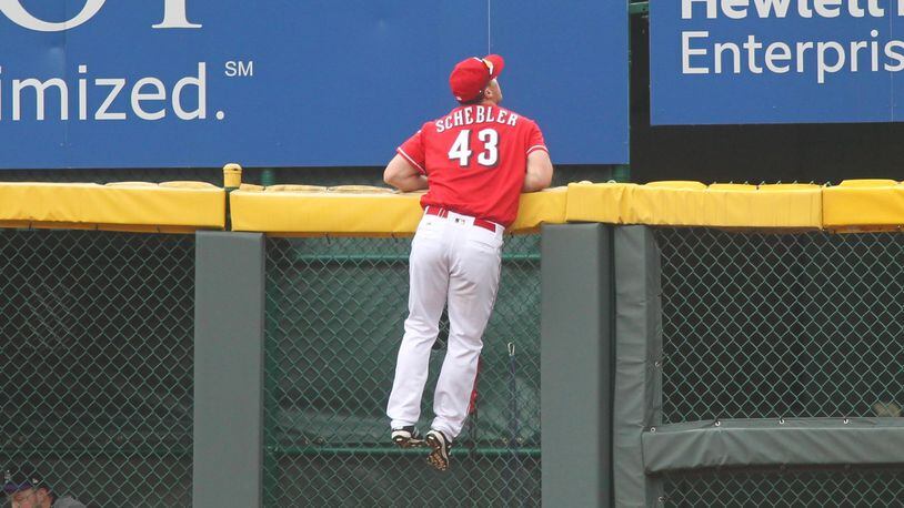 Reds right fielder Scott Schebler climbs the wall but can't get a home run hit by the Rockies on Sunday, May 21, 2017, at Great American Ball Park in Cincinnati. David Jablonski/Staff