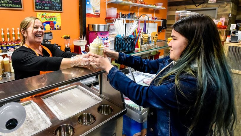 Missy Wagner, left, hands over a freshly made rolled ice cream to Emrie Adelhardt, 17, at Candy Stash Sweets & Treats Wednesday, Nov. 20, 2019 at 7125 Liberty Centre Drive in Liberty Township. Wagner opened Candy Stash in the space previously occupied by another candy shop. The location offers a variety of packaged and bulk candy, rolled ice cream, hand dipped ice cream, premium Philly Ice, specialty drinks and more. NICK GRAHAM/STAFF