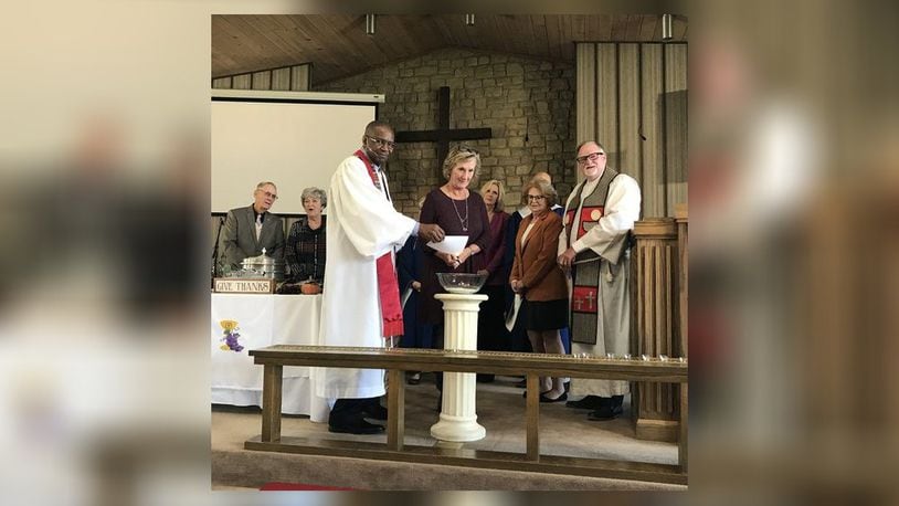 Pam Johnson, chairperson of Christ Church’s administrative team, lights a copy of the church’s mortgage, being held by Pastor Wynston Dixon, during a recent church service. SUBMITTED PHOTO