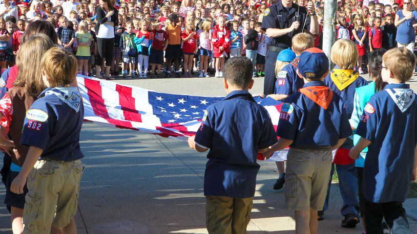 Fairfield South Elementary boys and girl scouts bring a new flag to Fairfield Fire Fighter Brian Rose during a 9/11 flag raising ceremony in front of the school, Tuesday, Sept. 11, 2012. Staff photo by Greg Lynch