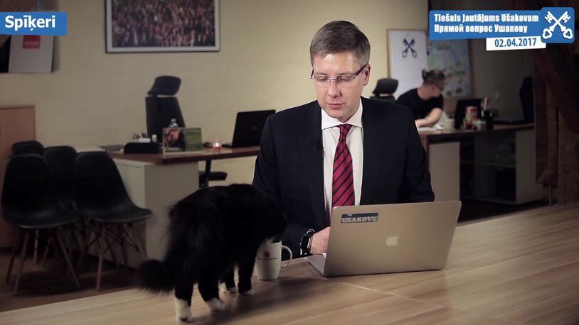 The Mayor of Riga Nils Usakovs looks down at his cat Dumka as it drinks from his cup while the mayor recording a video that was aired on Sunday April 2, 2017. (Nils Usakovs via AP)
