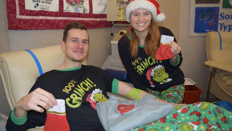 Christmas Eve blood drive donors Adam Al-Masri and Diane Dzieman show their fondness of the Grinch. On Al-Masri's lap is a gray fleece blanket that will be given to donors through New Year's Day.