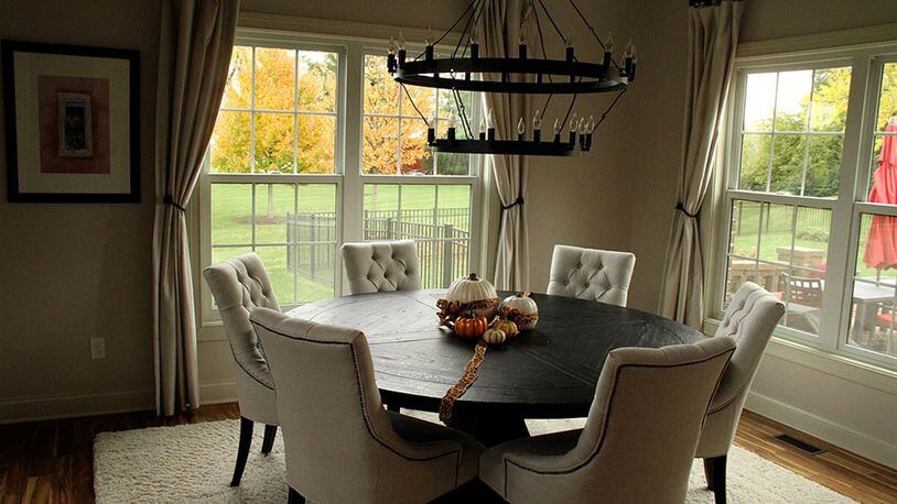 A large round wrought iron chandelier with multiple flame bulbs suggesting candles centers the dining room.