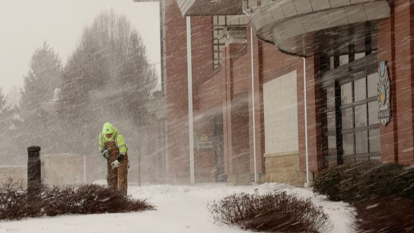 An Englewood Service Department employee shovels the sidewalk in front of the government center Thursday as heavy snow starts to fall.