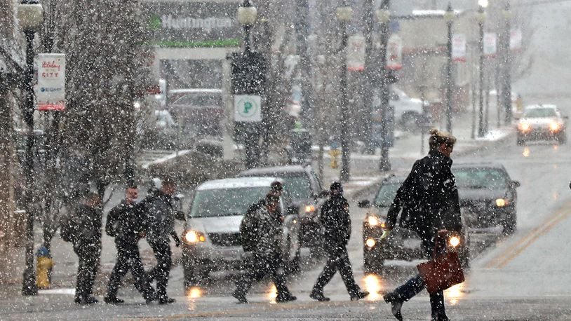 Pedestrians are silhouetted as they cross Fountain Avenue during a snow shower recently. BILL LACKEY/STAFF