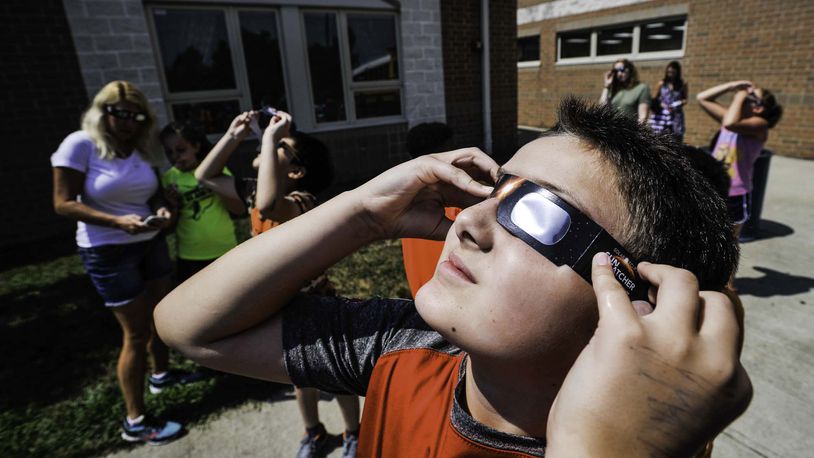Joel Bramblett, 11, a fifth grade student at Lakota's Endeavor Elementary School, views the solar eclipse through approved solar glasses Monday, Aug. 21 in West Chester Township. NICK GRAHAM/STAFF
