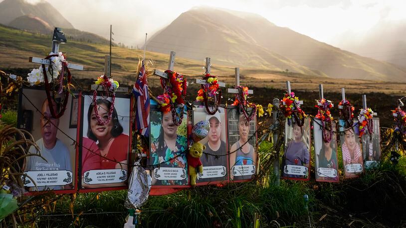 FILE - Photos of victims are displayed under white crosses at a memorial for the August 2023 wildfire victims, above the Lahaina Bypass highway, Dec. 6, 2023, in Lahaina, Hawaii. Hawaii health officials say test results show no evidence of widespread lead exposure from last summer's Maui wildfires. Blood samples were taken from more than 500 people to screen for lead after the deadliest U.S. wildfire in more than a century fire ripped through the town of Lahaina, killing 101 people. (AP Photo/Lindsey Wasson, File)