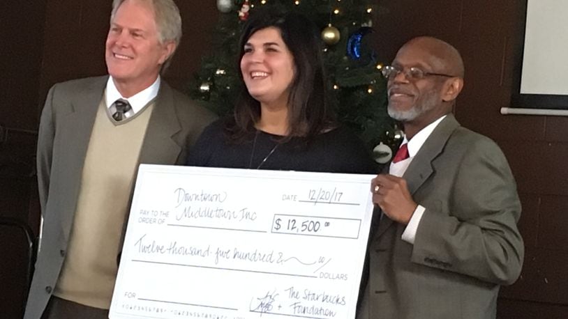 Ami Vitori, center, presents a $12,500 check to Phillip Harrison, left, board present of Downtown Middletown Inc., and Jeff Payne, DMI executive director. She won a $25,000 grant from Starbucks and split the grant between DMI and Community Building Institute. RICK McCRABB/STAFF