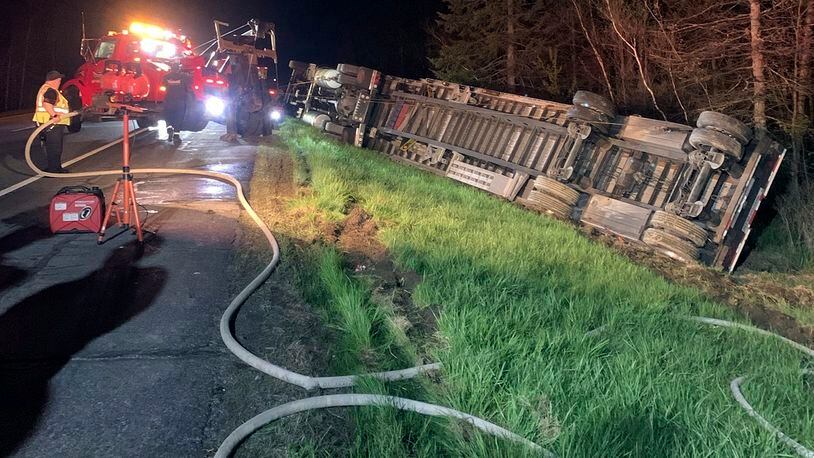 In this image provided by Maine State Police, emergency crews work to remove a tractor-trailer hauling 15 million bees to be used in pollinating the state's blueberry crops after it overturned on Interstate-95, Thursday evening, May 10, 2024, in Clinton, Maine. The driver was taken to a hospital and most of the bees were contained, officials said. (Maine State Police via AP)