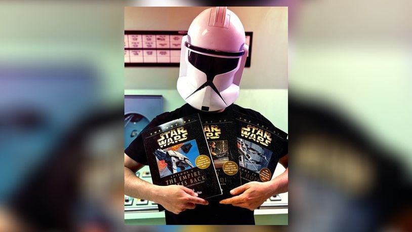 RiversEdge is launching a new family-friendly “Star Wars” movie night at 8:15 p.m. May 4 at 116 Dayton St., Hamilton. Pictured is Logan Walden in his Clone Trooper helmet holding up some Cosplay contest prize items donated from Unsung Salvage Design Company, in Hamilton. CONTRIBUTED