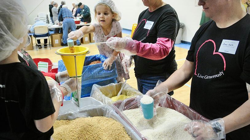 Over 140 volunteers from ages of 3 to 85 years old, packed over 35,640 meals Saturday, Jan. 20, 2024 for third world countries at the Abiding Christ Church in Fairborn. From left, Jennifer Dysert, Linda Kruse and Jason Health. MARSHALL GORBY\STAFF