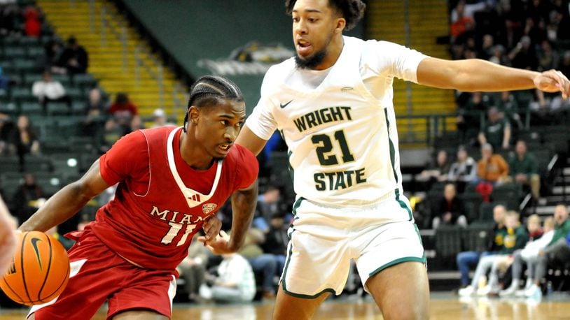 Miami's Mekhi Cooper, 11, drives past Wright State's Logan Woods, 21, during a nonconference game at Wright State's Nutter Center on Tuesday, Dec. 19, 2023. DAVID A. MOODIE/CONTRIBUTING PHOTOGRAPHER