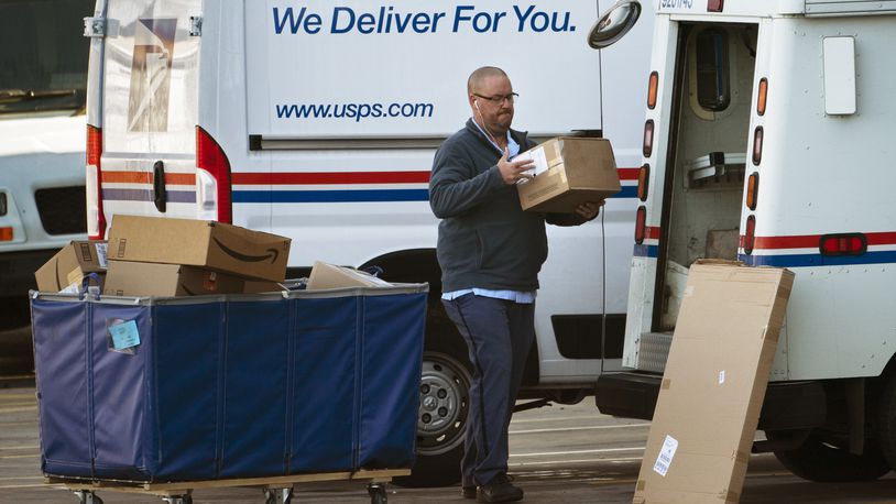 A postal carrier loads boxes into his delivery vehicle, Monday, Nov. 8, 2021, in Portland, Maine. AP FILE