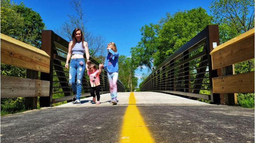 Darion Allen, Freya Smith, 1, and Riley Herzog, 8, walk on the recently completed section of the beltline project connecting Cleveland Avenue and Eaton Avenue Friday, May 14, 2021 in Hamilton. NICK GRAHAM/ STAFF