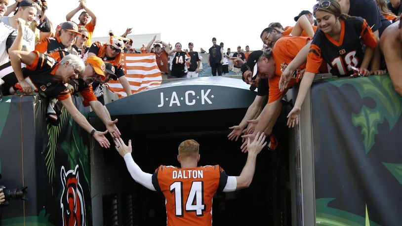 FILE - In this Oct. 7, 2018, file photo, Cincinnati Bengals quarterback Andy Dalton (14) high-fives fans as he leaves the field following an NFL football game against the Miami Dolphins in Cincinnati. The Bengals cleared the way for Joe Burrow to lead the team by releasing quarterback Andy Dalton, who holds several of the franchise’s passing records but couldn’t lead the woebegone Bengals deep into the playoffs. The move Thursday, April 30, 2020, gives Dalton, who had a year left on his deal, a chance to compete for a job with another team. (AP Photo/Frank Victores, File)
