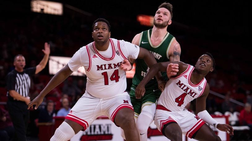 Miami’s Bam Bowman (14) and Isaiah Coleman-Lands (4) block out Wright State’s Bill Wampler during a game earlier this season. Miami defeated Wilberforce on Monday afternoon at Millett Hall. FILE PHOTO