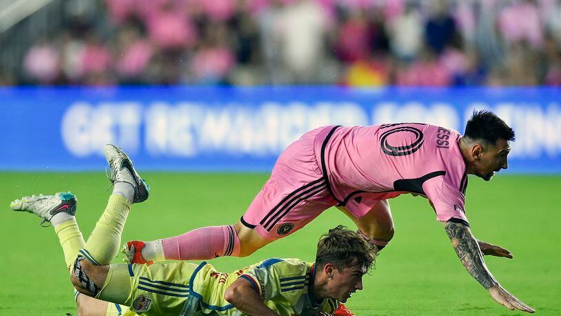 Inter Miami forward Lionel Messi falls on New York Red Bulls midfielder Daniel Edelman during the first half of an MLS soccer game, Saturday, May 4, 2024, in Fort Lauderdale, Fla. (AP Photo/Michael Laughlin)