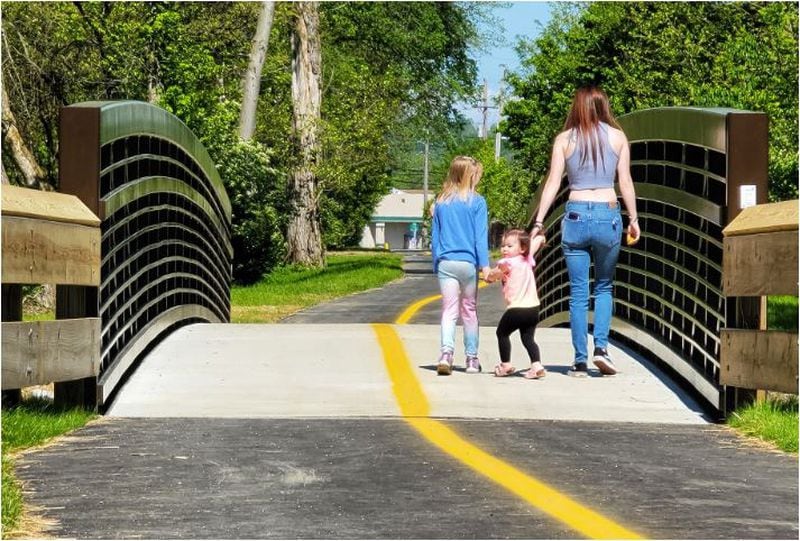 Darion Allen, Freya Smith, 1, and Riley Herzog, 8, walk on the recently completed section of the Beltline project connecting Cleveland Avenue and Eaton Avenue on Friday, May 14, in Hamilton. NICK GRAHAM / STAFF