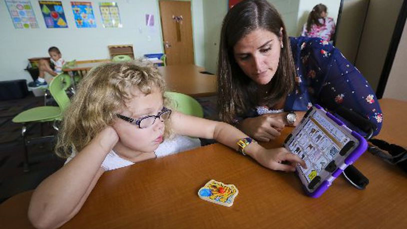 Anne Christian, Intervention Specialist, works with Bridgeport Elementary School student Riley Baker, who has autism and a rare chromosomal birth issue which has caused severe communication problems, communicates through a special machine and app with her teachers and parents. GREG LYNCH / STAFF