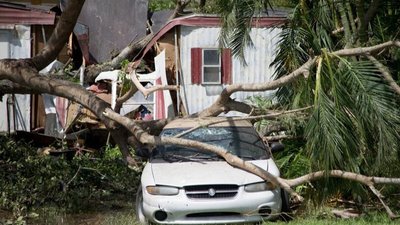 A mobile home and car crushed by a tree on NW 6th Street in Belle Glade, Florida on September 11, 2017. The home and car was damaged by hurricane Irma.