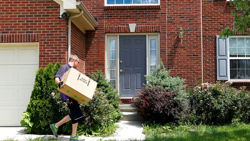 Travis Worrell delivers a package Wednesday, July 16, 2014, to a home in Liberty Twp. NICK DAGGY / STAFF