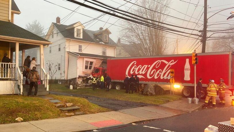 This photo provided by Jayson Wagner shows a tractor-trailer that jumped a curb and crashed into a house in suburban Philadelphia, early Saturday, Jan. 4, 20120. Officials spent Saturday morning trying to remove the bright red truck with a Coca-Cola logo on its sides from the twin home in Quakertown. Police say no one else was injured. (Jayson Wagner via AP) (AP)