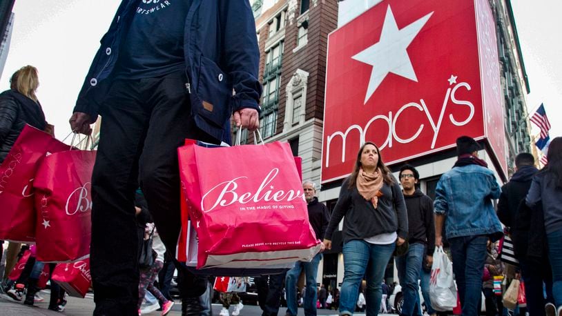 FILE - This file photo from Monday Oct. 17, 2016, shows shoppers and pedestrians in a crosswalk near a giant billboard next to Macy's flagship department store in Herald Square in New York. (AP Photo/Bebeto Matthews, File)