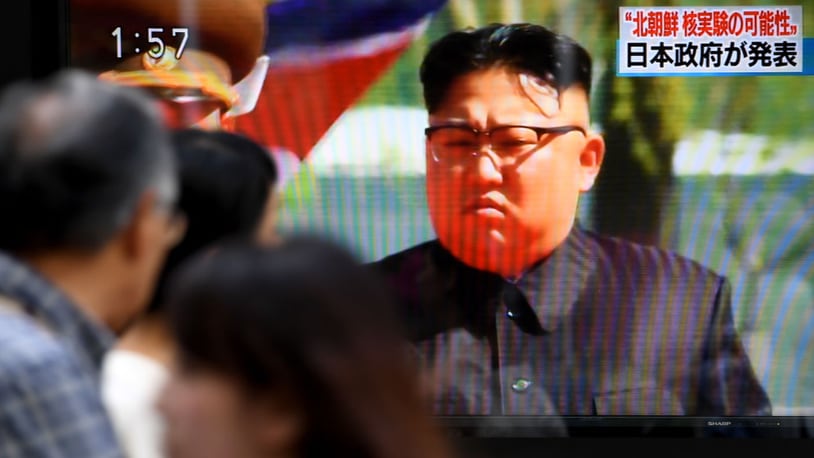 Pedestrians walk past a television screen broadcasting images of North Korean leader Kim Jong Un.