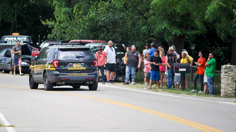 A Butler County Sheriff’s Deputy drives by a group of people on Elk Creek Road in Madison Township gathering to support the owner of a German Shepherd named Ruger that had to be put down from injuries sustained after a neighbor allegedly hit the dog with a baseball bat. NICK GRAHAM/STAFF