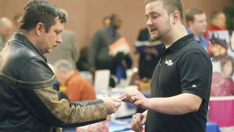Air Force veteran Bill Lamar, left, takes a card from Invertix senior technical recruiter Nathan Cargle at a job fair in 2014 hosted by the Military Veterans Resource Center at the Hope Hotel and Conference Center. TY GREENLEES / STAFF FILE PHOTO