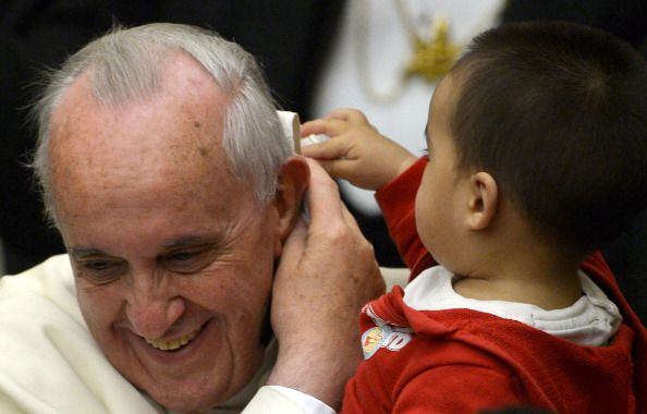 A child plays with Pope Francis' skull cap (December 14, 2013)