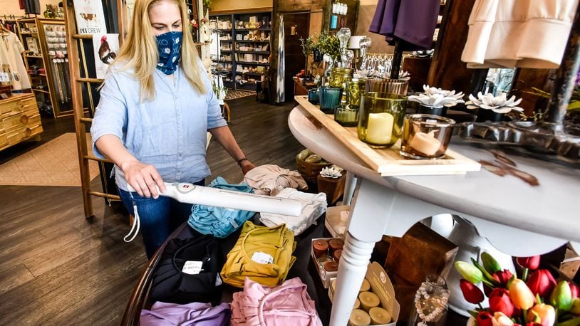 Debra Campbell at Fleurish Home on Main Street in Hamilton is using a UV light to sanitize products customers have touched and steaming garments tried on by customers as a measure to help combat germs in the store. NICK GRAHAM / STAFF