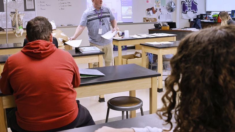 Science teacher Shawn Thomas passes out tests Tuesday to Middletown High School students. The district has implemented "Middie Minutes Matter," a plan school leaders hope lowers student absenteeism. ,NICK GRAHAM/STAFF