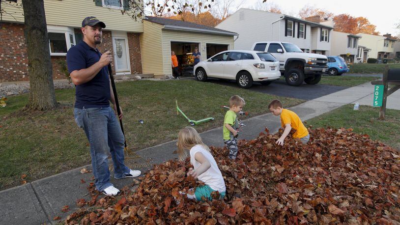 Greg Pekar rakes leaves with his sons Aidan, 10, and Jaxson, 2, along with their neighbor Constance Heeter, 7. Pekar and his wife Amanda, both 28, had no knowledge of the odor befouling the German Village neighborhood in Moraine where they just moved two weeks ago from Cleveland. CHRIS STEWART / STAFF